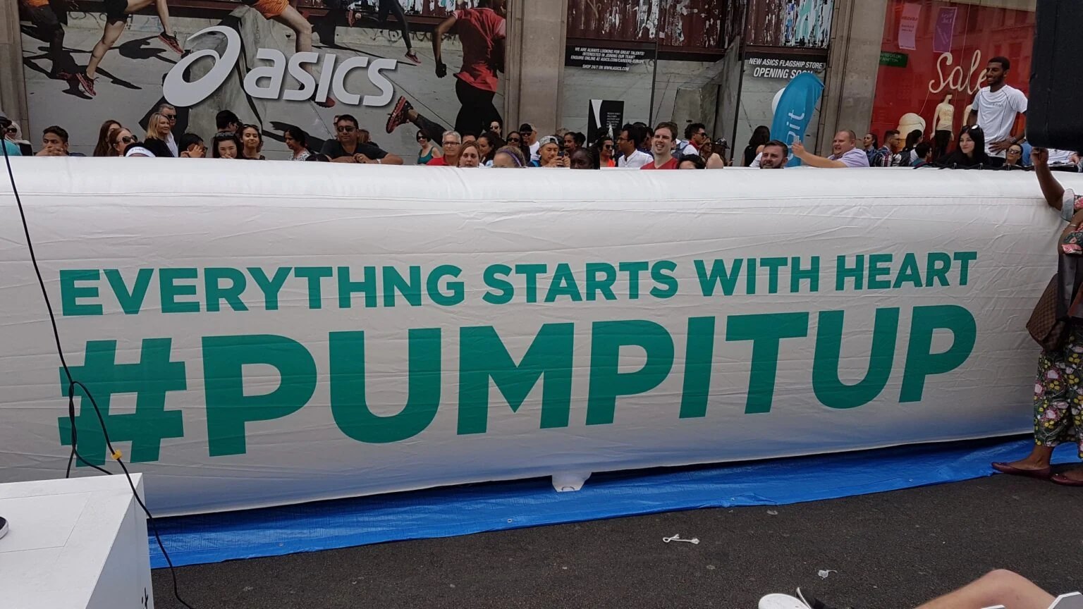 A giant white Fitbit banner on Regent Street with the words “Everything starts with heart” and the hashtag #PUMPITUP, with a crowd behind it